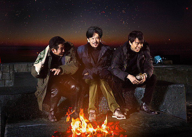 men sitting by fire laughing
