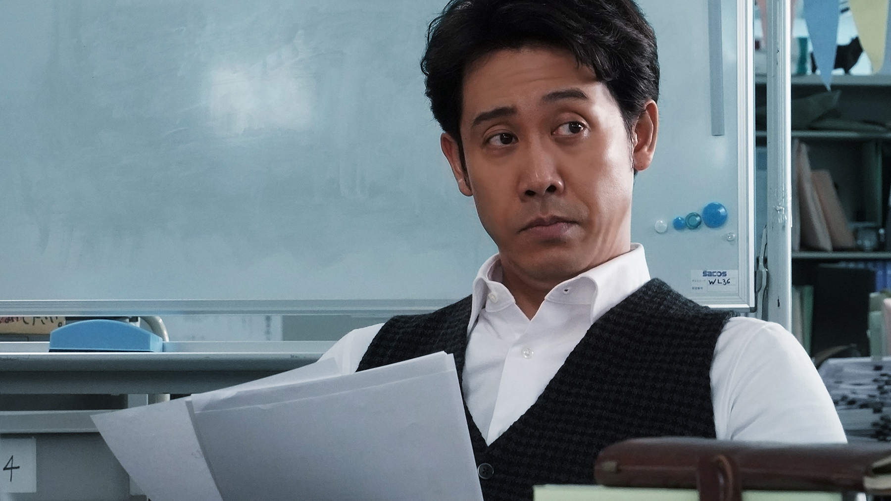 man sitting at desk holding papers