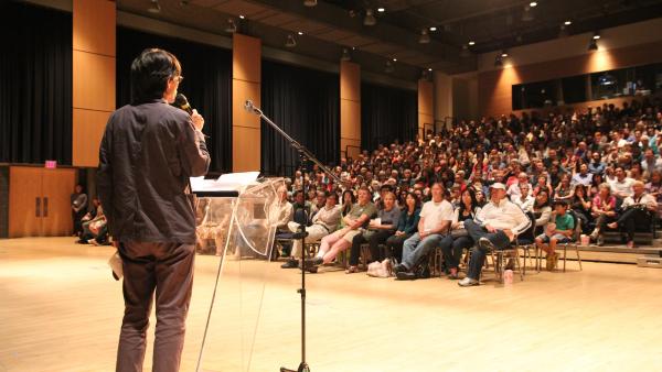 Man on stage speaking to crowd